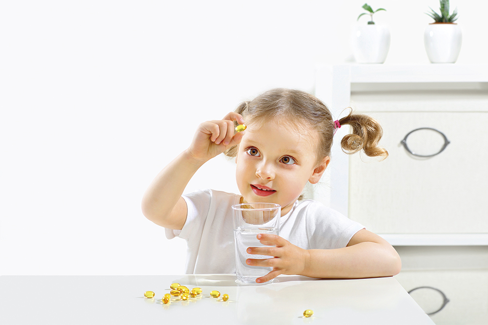 A,Child,Looks,At,A,Capsule,With,Fish,Oil,,Tastes